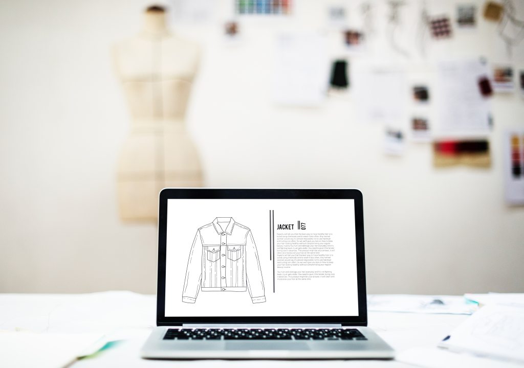Vector drawing of a denim jacket on a an open laptop with blurred image of a tailors dummy in the back of the room