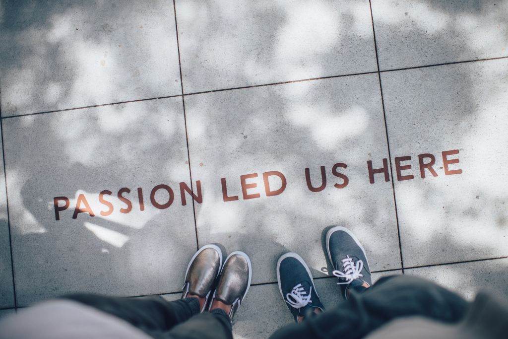 feet on a concrete paved floor with the words 'passion led us here' printed on them